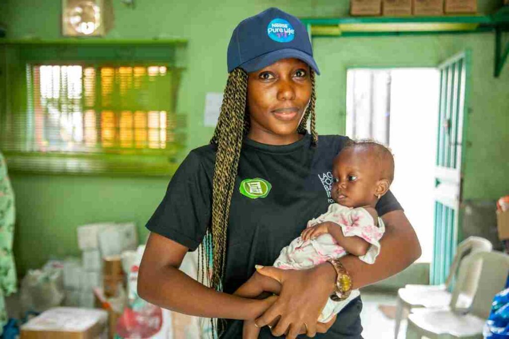 Volunteer holding a baby during a community healthcare and nutrition support program