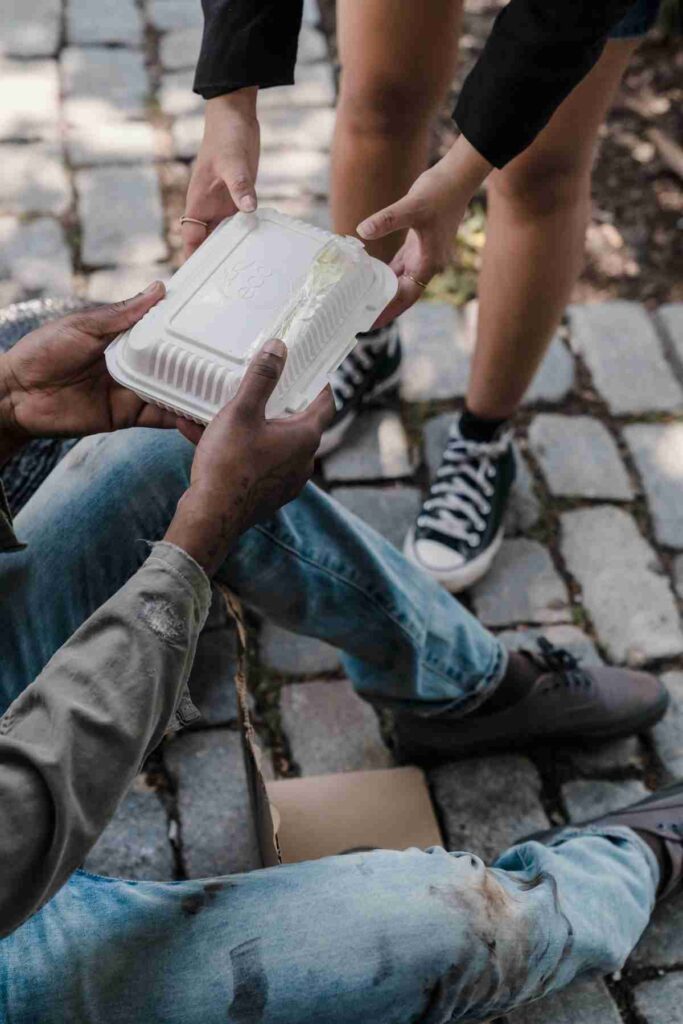 A volunteer giving a food box to a homeless person as part of a charity food donation program
