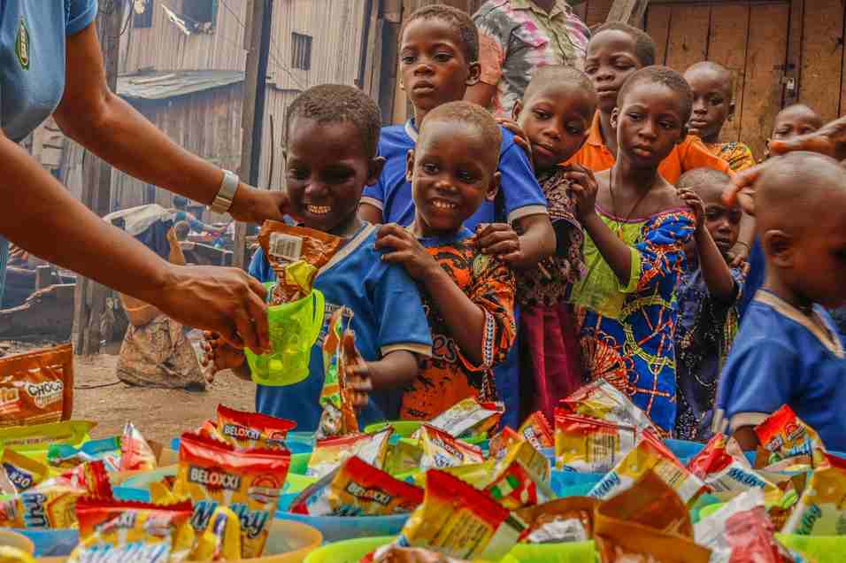 A charity volunteer distributing food packets to children during a community outreach program.