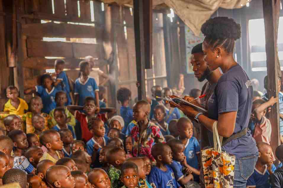 Volunteers teaching and supporting children in a community education program
