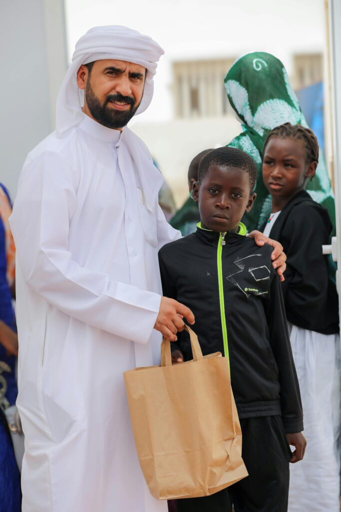 A charity representative standing with a child while providing support during a community outreach program.